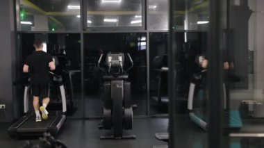 Fitness takip cihazı, kişisel eğitim, çalışma rutini. Spor salonu üyesi koşu bandında koşarak bacak kaslarını çalıştırıyor..