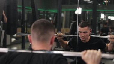 Halter egzersizleri, egzersiz diyeti, atletizm eğitimi. Halter boynunda ağırlıklarla çömeliyor, vücut geliştiren kişi sağlığa odaklanmış bir şekilde güçlü erkeksi bir hava sergiliyor.