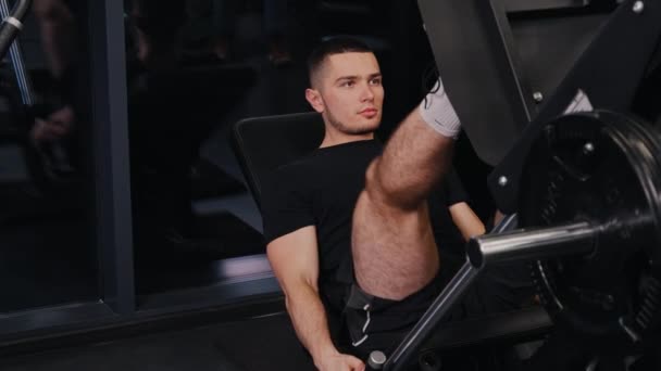 脚プレスマシンワークアウトアスレチックマン 魅力的な男性トレーナージムは足のプレス演習を実行します — ストック動画