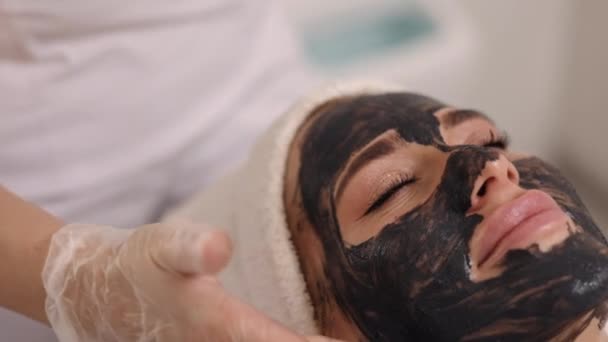 泥療法 アンチにきびケア ミネラルマスク 美容室 スキンケア専門家は 患者の顔に黒いマスクを適用します 解毒を促進します リフティング 昆布若返り 泥療法 — ストック動画