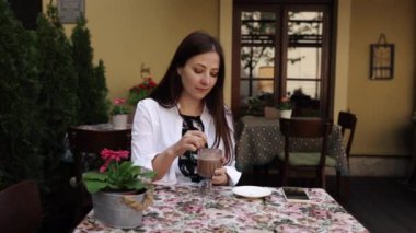 Kahve içmek, kapuçino içmek, nefis bir latte. Düşüncelerine dalmış bir kadın kafeteryada cappuccinonun tadını çıkarıyor..