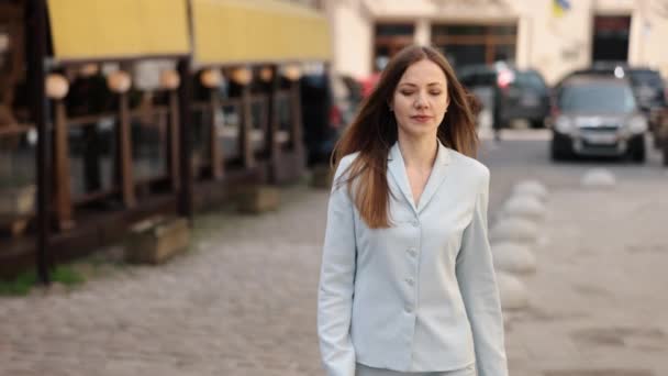 流动谈话 商务旅行 与人交谈 穿商务服装的女人在电话里大步走上街头 — 图库视频影像