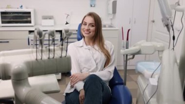 Female patient, Patient Wellbeing, Satisfied Woman. Content female patient is comfortably seated in chair at dentists office.