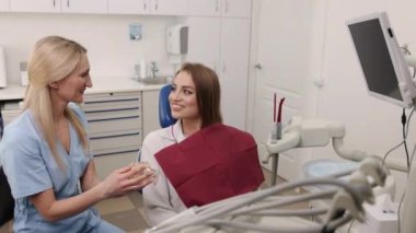Dental teeth, Jaw model, Patient guidance. Female patient focuses on dentists explanation of her treatment plan, made clear through use of teeth jaw model.