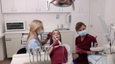Oral examination, dental expertise, dental care. Skilled dentist is making detailed examination of young womans oral cavity using intraoral camera.