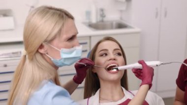 Dental technology, dental imaging, patient checkup. Intraoral camera assists dentist in examining oral cavity of young woman meticulously.
