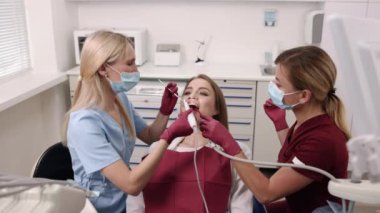 Oral inspection, young patient, patient examination. Professional dentist woman is scrutinizing young womans oral health using intraoral camera.