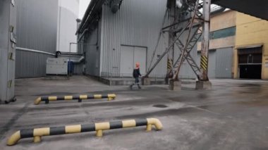 İşçi Güvenliği, Endüstriyel Operasyonlar, Yürüme Standartları. Büyük bir endüstriyel girişimde dışarıda yürürken koruyucu miğfer takan ve üniforma giyen işçiler görüldü..