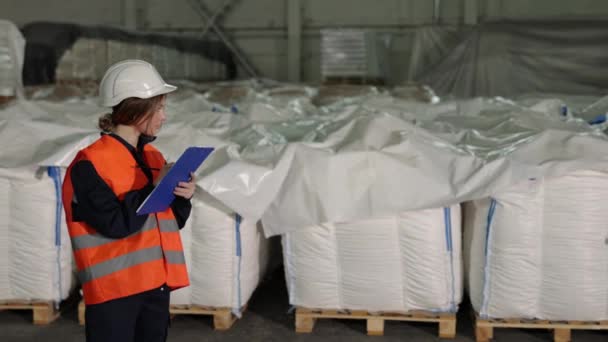 采购产品运输托盘 观察记录 工厂商品 厂里的女检查员仔细检查产品 列举白色的袋子 并写下便条 — 图库视频影像