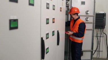 Robot makine, test ekipmanları, fabrika devreleri. Elektrikçi fabrika kontrol panelinde çoklu metre ile akım ölçümleri gerçekleştiriyor.