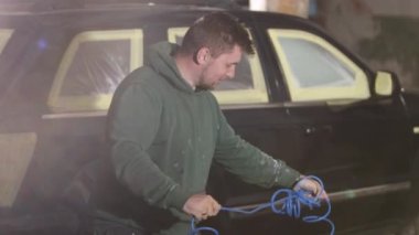 Boya hazırlama, araba boyama, boya spreyi. Erkek ressam arabayı boyamaya hazırlanıyor, hangi boyaya sprey sıkacağını çözüyor..