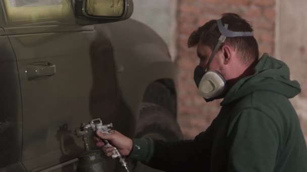 戴面具 安全面具 呼吸器面具 戴呼吸器的男子用喷枪喷漆积极地涂在汽车上 — 图库视频影像