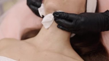 Nazik güzellik uzmanı, yatıştırıcı temizleyici, nemli bez. Temizleyici maddeyle nemli bez, güzellik uzmanları tarafından müşterilerin tenini nazikçe temizlemek için kullanılır..