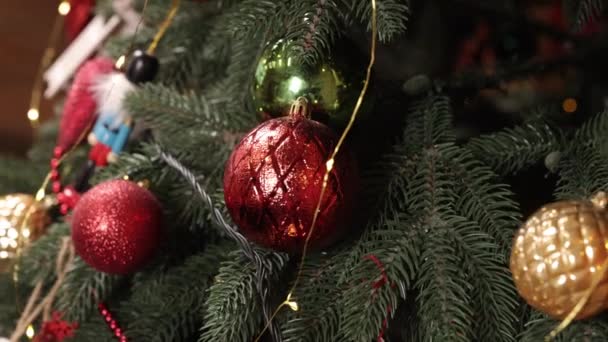 クリスマスのおもちゃ クローズアップ 人工クリスマスツリー バックグラウンドのクリスマスツリー クリスマスツリー上のボールのクローズアップ バックグラウンドのボケガーランド 新年のコンセプト クローズアップ — ストック動画