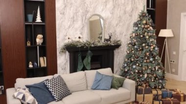 Noel için süslenmiş, çelenklerle süslenmiş mutlu tatiller. Noel ve yeni yıl, oturma odasında. Odanın ortasında süslenmiş bir Noel ağacı var. Hediyeler, iç mekan.