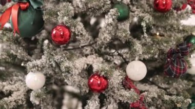 Yeni yıl konsepti, yakın çekim, parlak renkli ışıklar. Yoğun dekore edilmiş arka planda bulanık çerçeveli Noel ağacı. Ağaçtaki toplara yakın çekim. Arka planda Bokeh çelenkleri. Yeni yıl konsepti