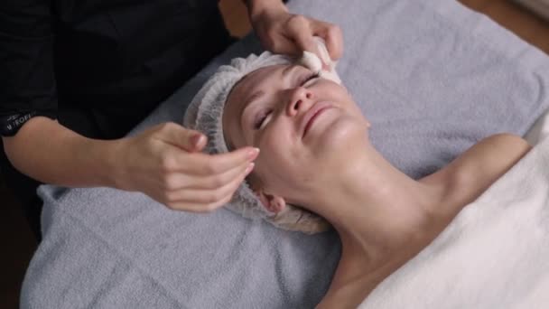 戴上面具 保持青春 美容师用餐巾擦去残留的面膜后 用毛巾擦拭客户的面部 — 图库视频影像