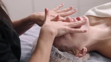 Salon spa, yüz kremi, güzellik uzmanı. Kadın güzellik uzmanı hastaların yüzüne güneş kremi sürmüş..