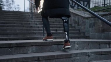 Bağımsızlık tırmanışı, sakatlık gururu, protez bacak. Şehir caddesinde merdivenleri çıkma işi protez bacaklı engelli bir adam tarafından tamamlandı..