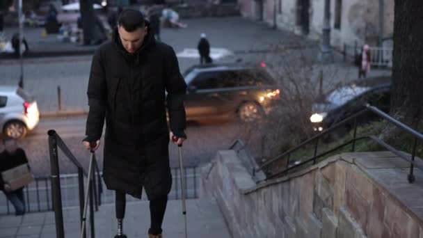 身体障害者運動 人工脚 義足を持つ男性は 市街地の階段を上昇しながら手すりを使用しています — ストック動画
