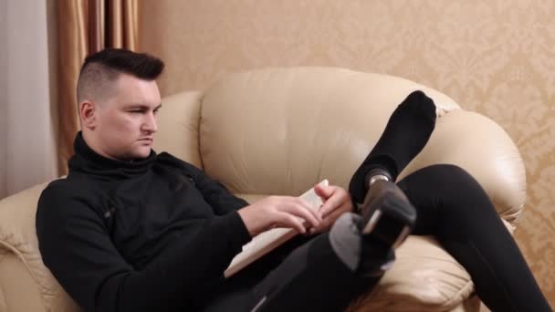 休闲活动 室内阅读 假腿患者花时间在沙发看书上 — 图库视频影像