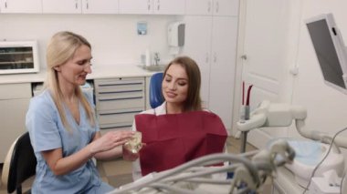 Düzeltmeden önce, kadın hasta, diş modeli. Hasta dişçi diş çene modeli kullanarak tedavi planını açıklarken dişçiyi çok iyi dinliyor..