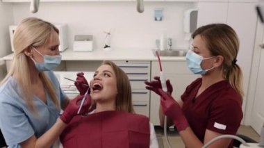 Diş hekimi çalışıyor, sözlü muayene, diş kontrolü. Diş sağlığı konusuna değinen doktor, potansiyel çürüme için ağız boşluğunu inceleyerek, taşıyıcı hastalıkların önlenmesi ve tedaviye ilişkin tavsiyelerde bulunur..