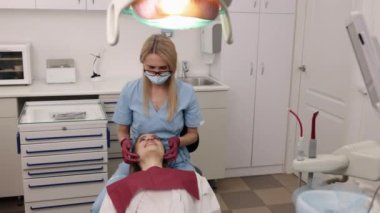 Kadın ortodonti, ortodontik değerlendirme, çene değerlendirmesi. Ortodontist-gnatholojist kadın çene eklemlerini elden ele değerlendiriyor.