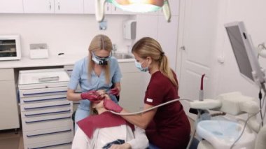 Ultraviyole ışık, diş tedavisi, diş sağlığı kliniği. Dişçi kliniğinde, stomatolog morötesi ışığı hastaların dişlerine fotopolimer uygular..