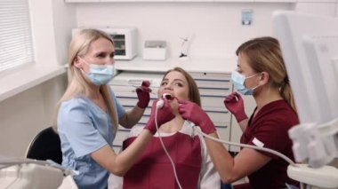 Diş aletleri, oral sağlık, oral bakım. Deneyimli diş hekimi genç kadınların ağız boşluklarını incelemek için intraoral kamera kullanıyor..
