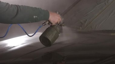 Araba servisi, araç tamiri, oto boyama. Solunum cihazıyla donatılmış, sprey tabanca kullanarak arabaya taze boya sürüyor..