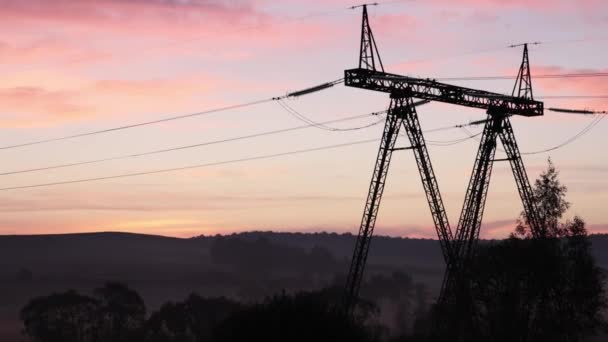 タワーの影 スチールパイロン エネルギーストリーム 日の出は田園電力網のためのインフラを提供する鋼鉄ピロンの長い影を投げました — ストック動画