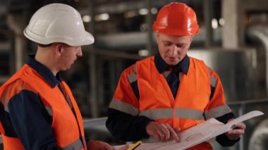 Plan güncellemesi, fabrika planları, teçhizat planları. Üretim tesisinde, mühendis ve işçi inşaat planlarını ortaklaşa değerlendirir.