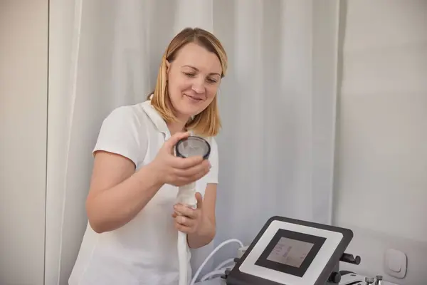 vacuum massage, Anti Cellulite Massage, beauty center. At beauty medical clinic, beautician gets ready to perform vacuum Anti Cellulite Massage, holding distinct nozzle for process.