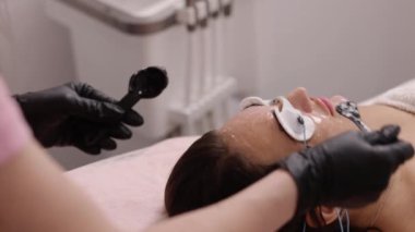 Kadın derisi, temas jeli, steril eldivenler. Epilasyondan önce kadın yüzüne ultrason jeli uygulayan kozmetikçi, Esthetisyen kadın derisini lazer tüy aldırma tedavisi için hazırlıyor,