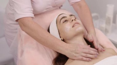 Cilt bakımı uzmanı, yüz tedavisi, masaj yardımları. Müşterilerin yüzüne krem sürerken, kadın kozmetikçi canlandırıcı masaj tedavisi uyguladı.