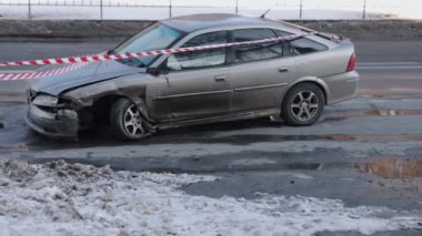 Kaza sonrası, çarpışma hasarı, araba kazası. Otomobil, ön tarafı kazayla parçalanmış, uyarı bandıyla kapatılmış..