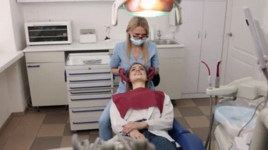 Kadın hasta, diş bakımı, hasta kontrolü. Diş eklemli kadın ortodonti ve gnatholoji konusunda uzman doktor tarafından elle muayene ediliyor..