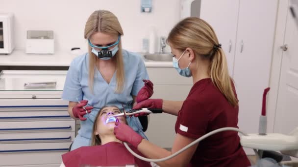 修復歯 セラピールーム 歯科Uv 歯の修復と治療中に 腸内科医は 歯科オフィスの紫外線を用いた光合成塗装歯を照らしています — ストック動画