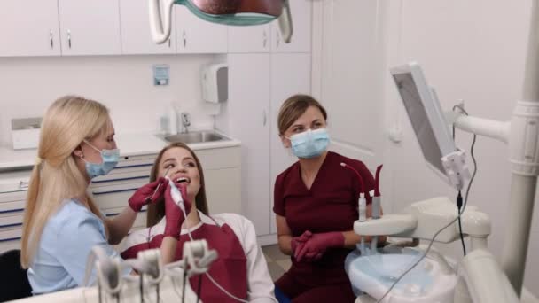 照相机检查 牙齿健康 口腔照相机 年龄较大的牙医正在用口腔内摄像机对年轻女性的口腔进行彻底检查 — 图库视频影像