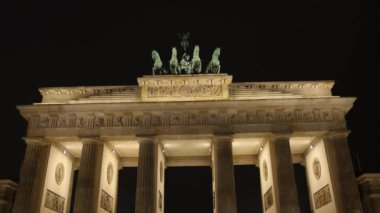 Kapı Parıltısı, Alacakaranlık Güzelliği, Berlin Aydınlanması. Görkemli bir şekilde aydınlatılan Brandenburg Kapısı, karanlık gökyüzüne karşı duruyor..
