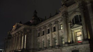 Bayrak aydınlatma, gece fotoğrafçılığı, mimari ışıklandırma. Aydınlanmış Reichstag Binası 'nın etrafında bayraklar dalgalanıyor..