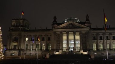 Reichstag turizmi, bayraklı bina, aydınlanma manzarası. Germanys Reichstag Binası geceleri ışıltılı ışıklar ve ulusal bayraklarla canlanıyor..