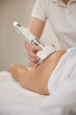 Güzellik prosedürü, elektroporasyon masajı, selülit düzeltme. Profesyonel güzellik kliniğinde anti-selülit masajı yapılıyor ve kozmetikçiler müşterilerine masaj yapmak için paten kullanıyor.