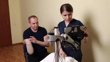Engelli adam, Rehabilitasyon yenilikleri, Hareket onarımı. Odaklanmış fizyoterapist, rehabilitasyon sırasında gelişmiş robotik ekipman kullanmakta ve erkek hastaya yardımcı olmaktadır.