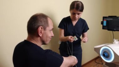 Terapi elektrotları, kol terapisi, kas terapisi. Tam donanımlı bir tıbbi tesiste odaklanmış terapist erkek hastaların kol kaslarını tedavi etmek için son teknoloji elektroterapi aletleri kullanır..
