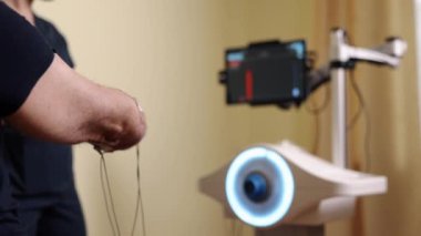 Kolu kesilmiş, hareket yardımı, robot terapisi. Profesyonel terapist, hasta bakımına odaklanmış, klinik bağlamda yenilikçi robotik cihazlar kullanarak insanı kol rehabilitasyonuna yönlendiriyor..