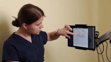 Tedavi rejimi, rehabilitasyon verileri, iyileşme analizi. Tıp kliniğinde, terapist interaktif dokunmatik ekranda hasta rehabilitasyonunun ilerlemesini inceliyor.