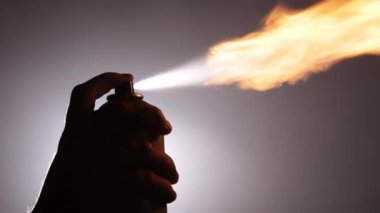 Gaz maskesi, yangın önlemi, Alev sanatları. Loş, sisli alanda, insanların silueti dramatik alevleri serbest bırakmak için sprey kullanırken koruyucu maske takarken görülür..