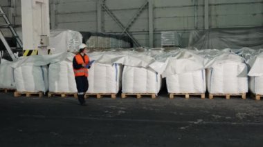 Gıda Üretimi, Denetim Süreci, Fabrika Müfettişleri. Fabrikadaki bayan müfettiş denetleme yapar, beyaz mal torbalarını ölçer ve bulgularını belgeler..